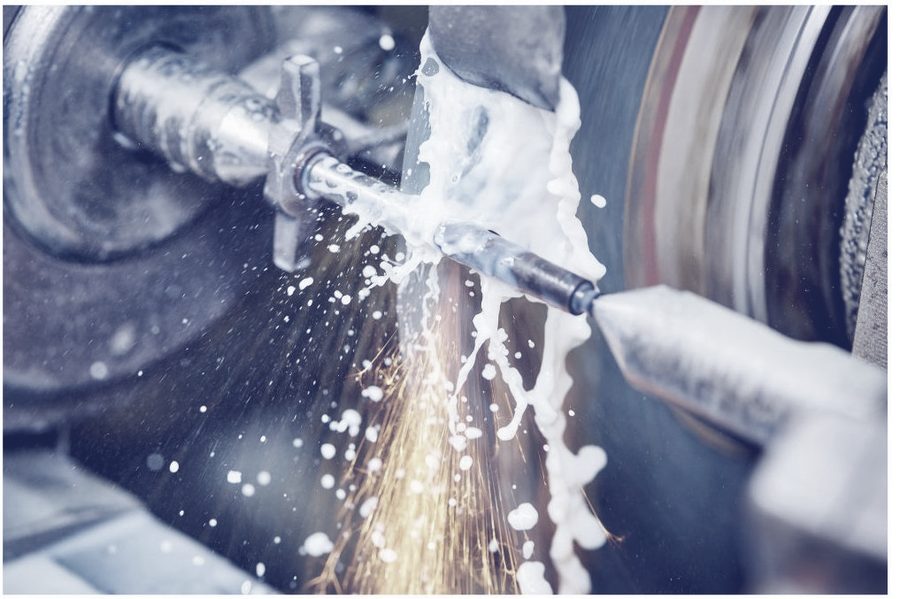 Coolant spraying over a metal part on a lathe