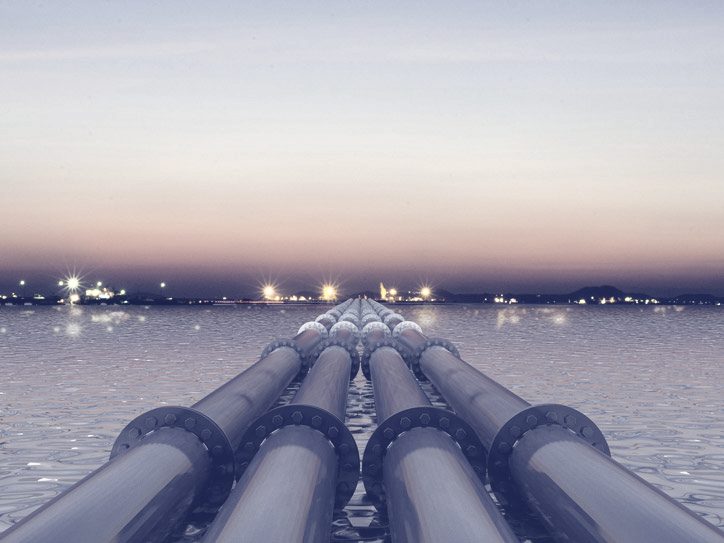 Pipelines running out over water at dusk